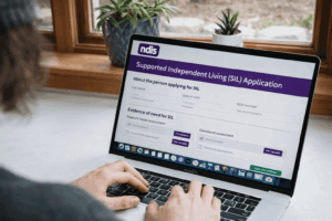 Person completing an NDIS Supported Independent Living SIL application form on a laptop, showing eligibility details and required evidence for SIL funding